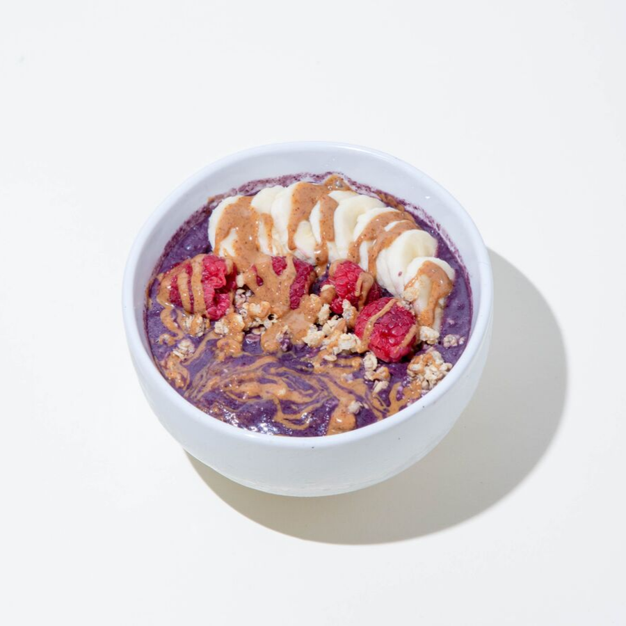 a bowl of energizing acai smoothie topped with slices of berry, banana, and oats 